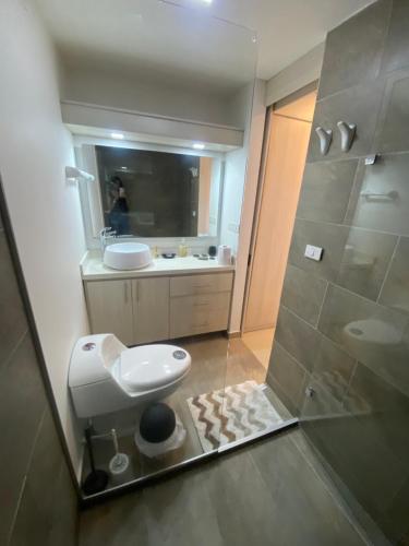 une salle de bain avec toilettes, lavabo et miroir dans l'établissement Apartasuite moderna - en el corazón del poblado medellín, à Medellín