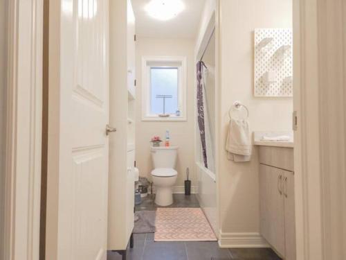 a white bathroom with a toilet and a window at Inspired Stay close to Niagara *4B & 2King Beds* in Thorold