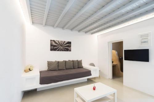 a white bedroom with a bed and a table at Brand New Mykonos Town Suites in Mikonos