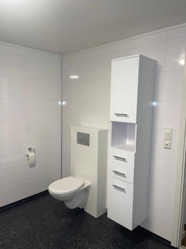 a bathroom with a toilet and a white cabinet at Family-Friendly Apartment close to the beach in Rød