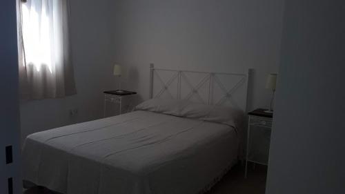 a bedroom with a white bed and two night stands at Cabañas Teodoro in Tanti