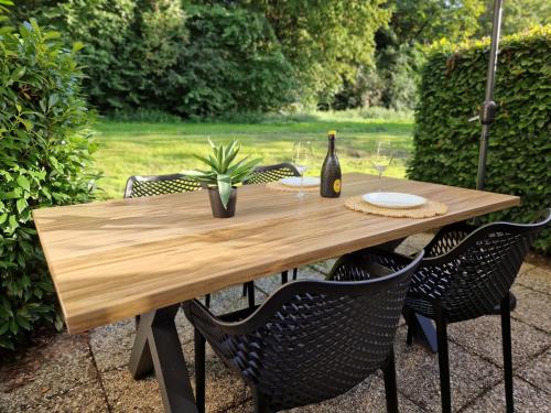 een houten tafel met stoelen en een fles wijn bij Steef's vakantiehuis zuid limburg in Simpelveld