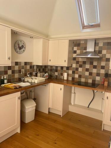 a kitchen with white cabinets and a sink at Iffin Farmhouse in Canterbury