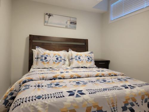 1 dormitorio con cama con cabecero de madera y almohadas en 2-Bedroom Guest Suite en Calgary