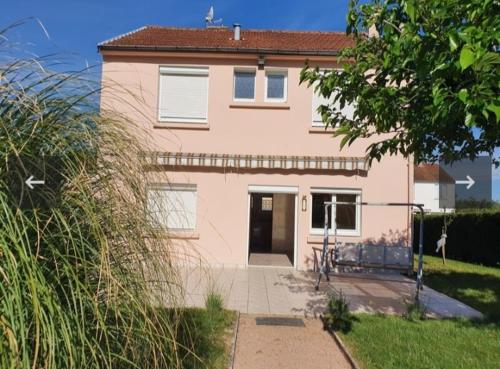 ein rosa Haus mit einem Fahrrad davor geparkt in der Unterkunft La maison ensoleillée in Lapalisse