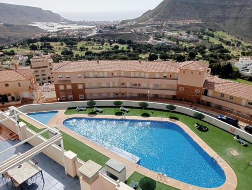 a resort with a large swimming pool and mountains in the background at Golf, piscina climatizada y playa in La Envia