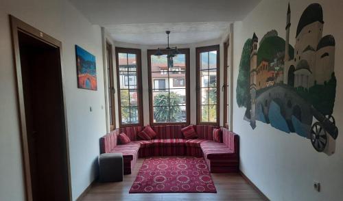 Comfort Hotel Prizren في بريزرن: غرفة معيشة مع أريكة وردية أمام نافذة