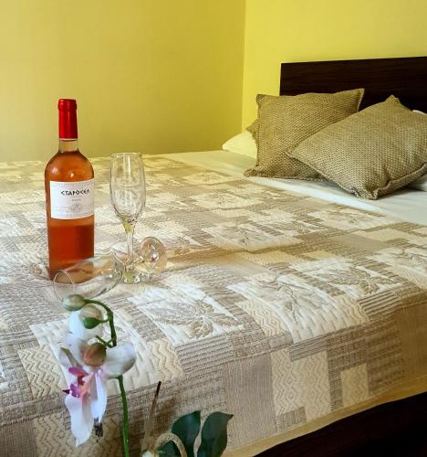 にあるКАРИАНА хотелのベッドの上にワイン1本、グラス1杯、花1本