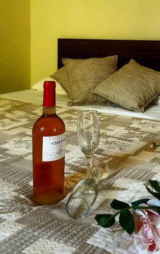 a bottle of wine and a glass on a bed at КАРИАНА хотел 