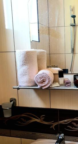 a shelf with towels and a mirror in a bathroom at КАРИАНА хотел 