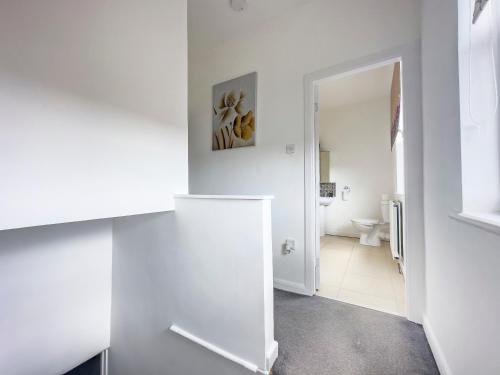 a white room with a toilet and a hallway at Luxury and lovely Cosy well equipped home with Free Parking and Free Fast WiFi in Morley