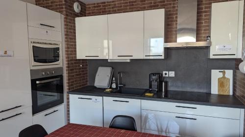 une cuisine avec des armoires blanches et des appareils électroménagers blancs dans l'établissement Les Salins à Sète proche plages, à Sète