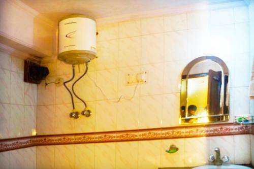 een badkamer met een lamp op de muur en een spiegel bij Hotel Maharaja Continental - New Delhi in New Delhi