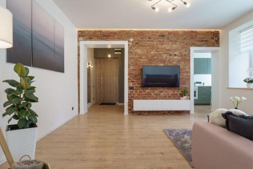 een woonkamer met een bakstenen muur en een tv bij Centra apartamenti in Liepāja