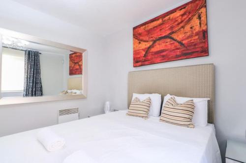 a bedroom with a white bed with a painting on the wall at Glamorous Central Apartment in London