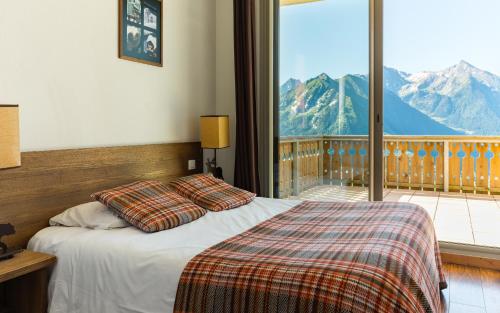 a bedroom with a bed and a balcony with mountains at Lagrange Vacances Les Chalets de l'Adet in Saint-Lary-Soulan