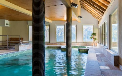 an indoor pool in a house with windows at Lagrange Vacances Les Chalets de l'Adet in Saint-Lary-Soulan