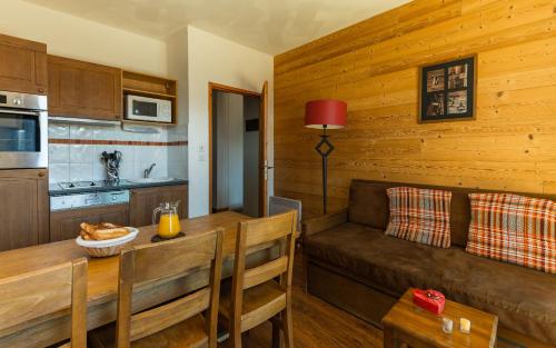 a kitchen and a living room with a table and a couch at Lagrange Vacances Les Chalets de l'Adet in Saint-Lary-Soulan