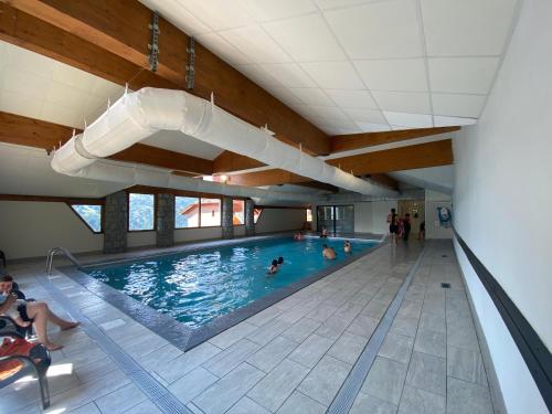 une grande piscine avec des gens dans l'eau dans l'établissement Appartement 4-6 personnes à Valmeinier 1800 résa du samedi au samedi avec piscine intérieure chauffée, à Valmeinier
