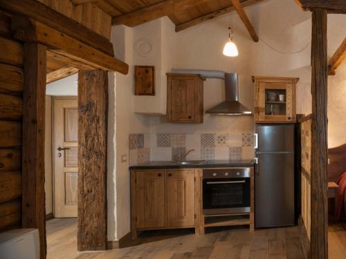 een keuken met houten kasten en een roestvrijstalen koelkast bij Appartements Moraine Enchantée - CIR 82 CIR 83 in Aosta