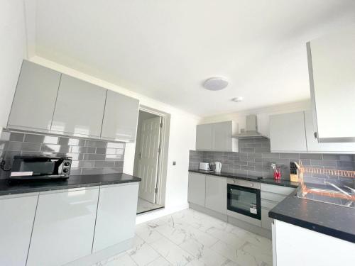 a kitchen with white cabinets and black counter tops at New Florence Rooms in Mitcham