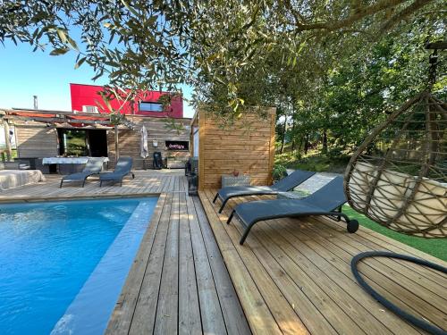 a wooden deck with a swimming pool and a swing at La cabane d’ED in Lafrançaise