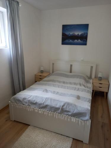 a white bed in a bedroom with two night stands at Plitvice Valley Apartments in Ličko Petrovo Selo