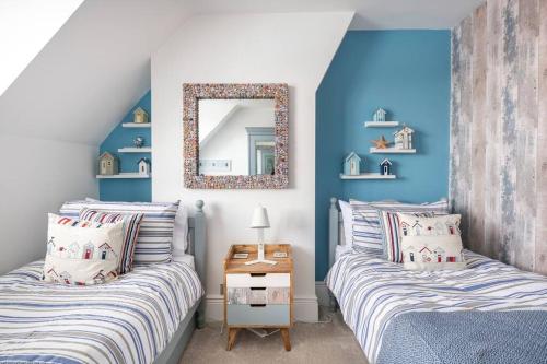 a bedroom with two beds and a mirror on the wall at Beautiful Spacious Beach Home Newly Renovated in Felixstowe