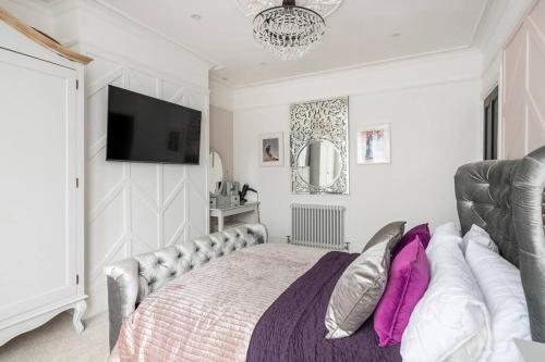 a bedroom with a bed and a tv on the wall at Beautiful Spacious Beach Home Newly Renovated in Felixstowe