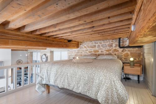 1 dormitorio con cama y pared de piedra en Le Cocon Pacôme Les Autres, en Lyon