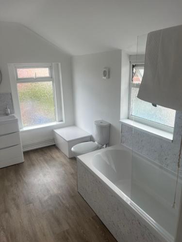 uma casa de banho branca com uma banheira e uma janela em Seaside Paradise em Lowestoft