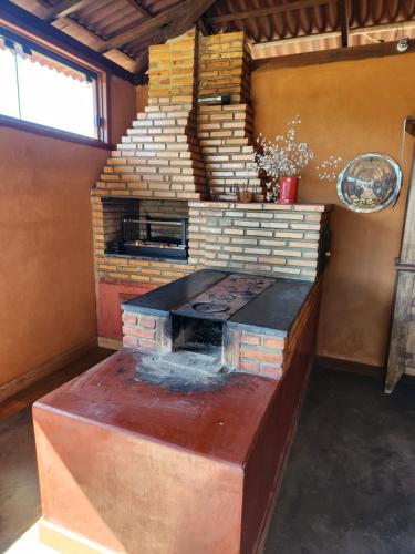 uma cozinha com um fogão de tijolos num quarto em Chales Sitio dos Ventos em Lavras Novas