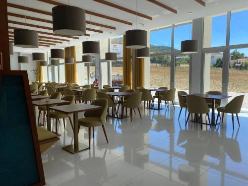 a dining room with tables and chairs and windows at Hotel Pedras Salgadas in Pedras Salgadas