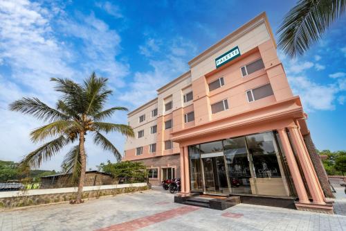 un hotel con una palmera delante en Palette - Coastal Grand Hotels & Resorts, OMR en Chennai