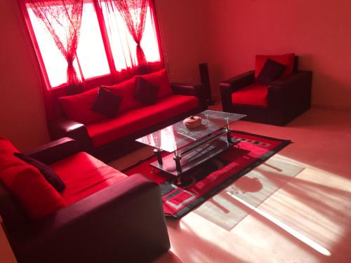 una sala de estar con 2 sofás rojos y una mesa de cristal. en Résidence ASSAFA 3 AGADIR Familiale, en Agadir