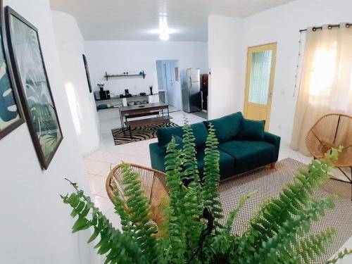 a living room with a green couch and a plant at Casa central aconchegante in Alto Paraíso de Goiás