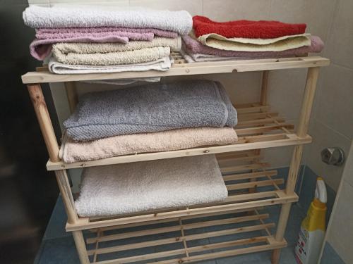 uma pilha de toalhas numa prateleira de madeira na casa de banho em CASA VACANZE : CASA FORTUNA em Taranto