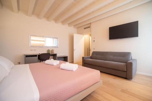 a bedroom with a bed and a couch and a television at Calcirelli Suites in Verona