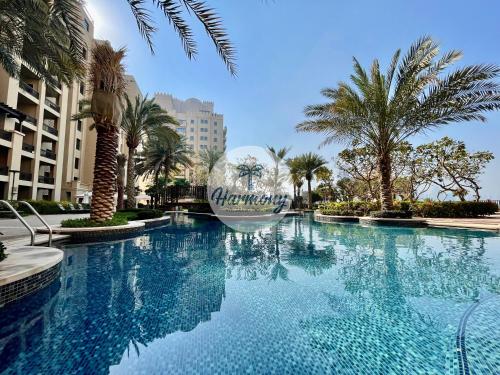 a large swimming pool in a resort with palm trees at Harmony Vacation Homes - South Residence in Dubai