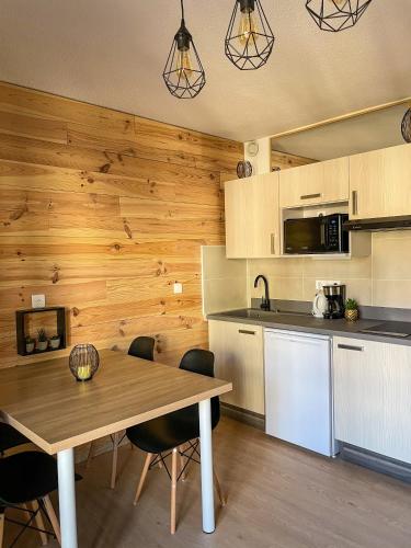 - une cuisine avec un mur en bois, une table et des chaises dans l'établissement Chalereux studio a la montagne, à Auron