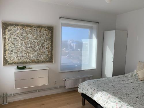 1 dormitorio con ventana grande y 1 cama con colcha en Lottas Beautiful Penthouse Apartment, en Malmö