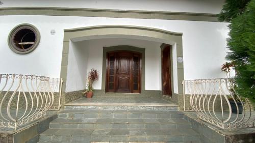 een voordeur van een wit huis met een trap bij Quarto aconchegante II in Cruzeiro