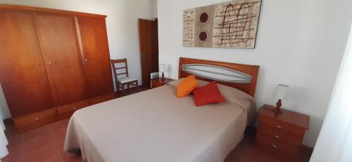 Ribeirinha的住宿－Casinha do Chorão，卧室配有白色床和2个橙色枕头
