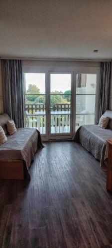 une chambre avec deux lits et une grande fenêtre dans l'établissement La Perle de l'Océan, à deux pas de la mer sans route à traverser, parking privé, piscine, à Arzon