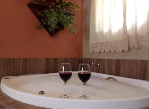 two glasses of red wine sitting on a bath tub at Pousada recanto Lajinha maua in Resende