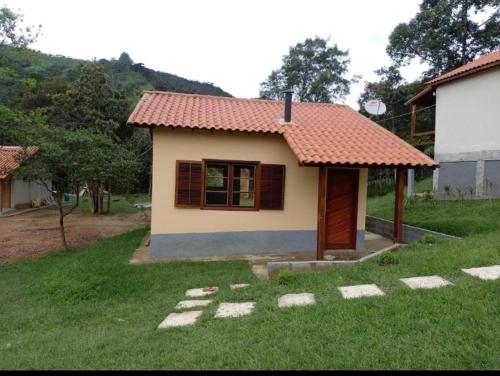 a small house with a red roof in a yard at Pousada recanto Lajinha maua in Resende