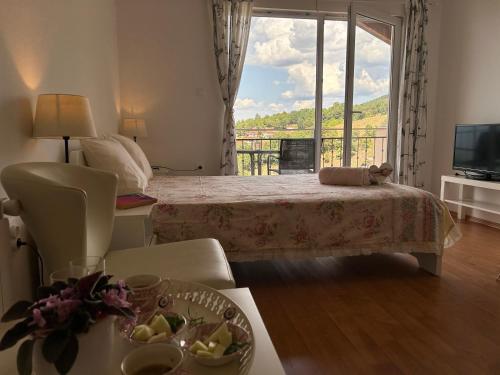 a bedroom with a bed and a balcony with a television at Villa Chingo in Ohrid