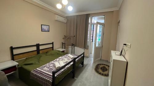um quarto com uma cama verde e uma janela em Guest House Kldiashvili em Batumi