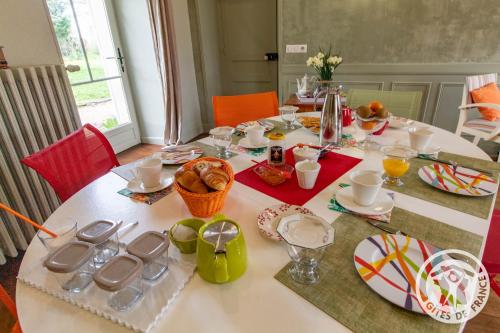 mesa de comedor con mantel blanco y comida en Manoir d'Orbé, en Montreuil-Bellay