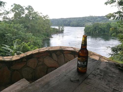 Una botella de cerveza sentada en una mesa junto a un río. en Nileit Campsite Jinja en Jinja